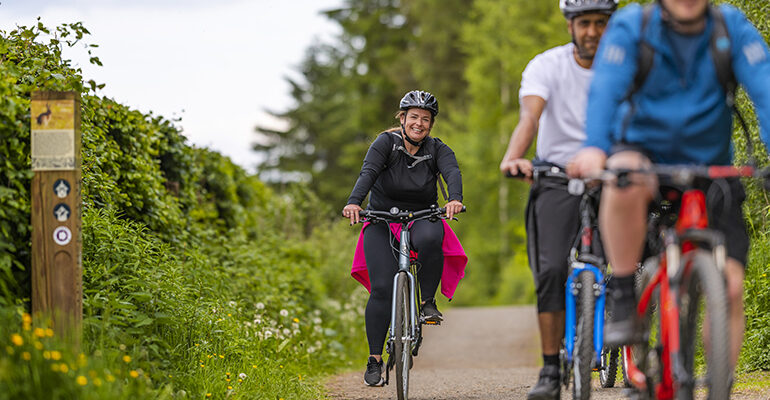 Une femme fait du vélo sur une piste cyclable de campagne