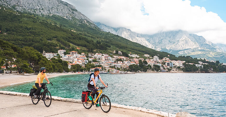 Un couple de cycliste sur une piste cyclable bordée par la mer