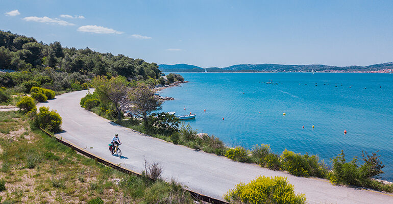 Un cycliste roule le long de la côte et sa mer turquoise