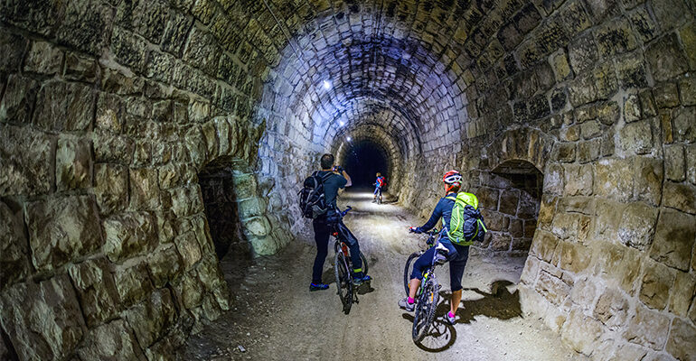Un groupe de cycliste traverse un tunnel de pierres