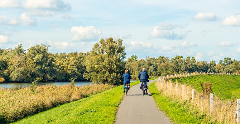 Deux cyclistes roulent en campagne le long d'une rivière