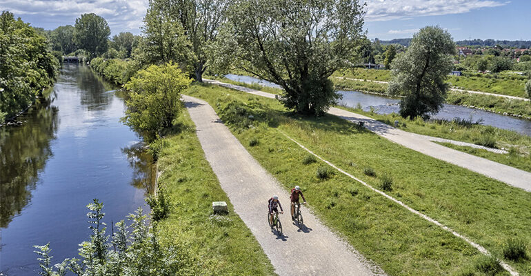 Deux cyclistes sur une piste cyclable entre deux rivières