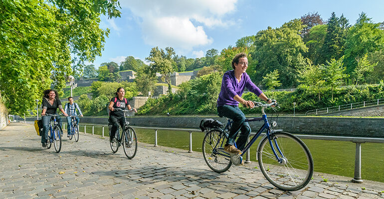 3 cyclistes roulent sur les bord de rivière pavés