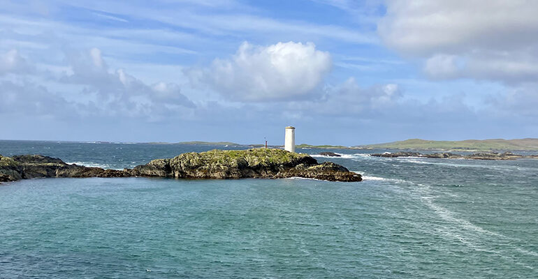 Vue sur un phare blanc sur sa petite île rocailleuse