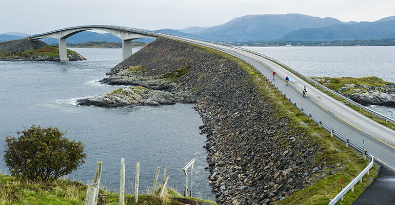 Un groupe de cycliste traverse un long pont sur la mer rejoignant une île