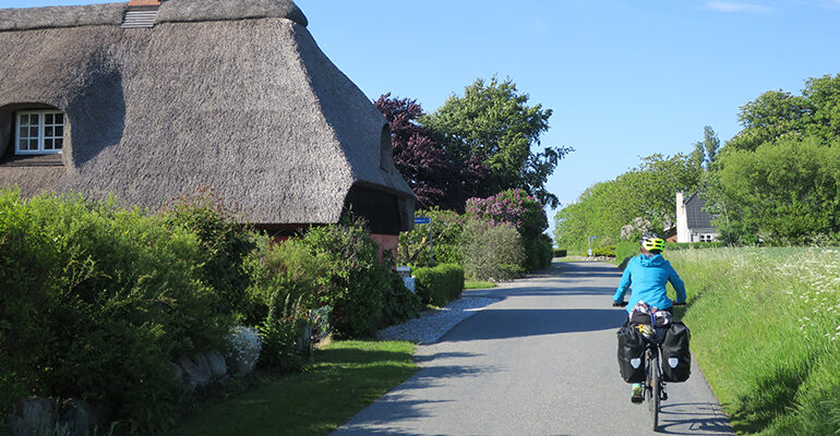 Un cycliste roule sur une route de campagne au Danemark
