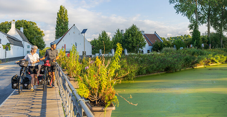Un couple de cycliste traversent un pont sur le canal
