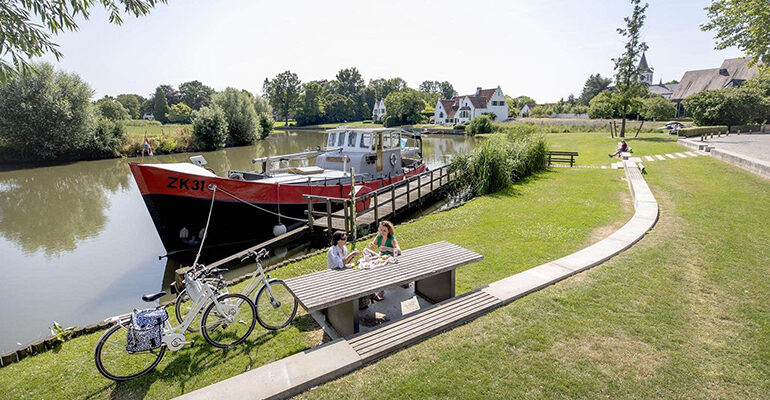 Deux cyclistes se repose sur une table de pique-nique au bord du canal
