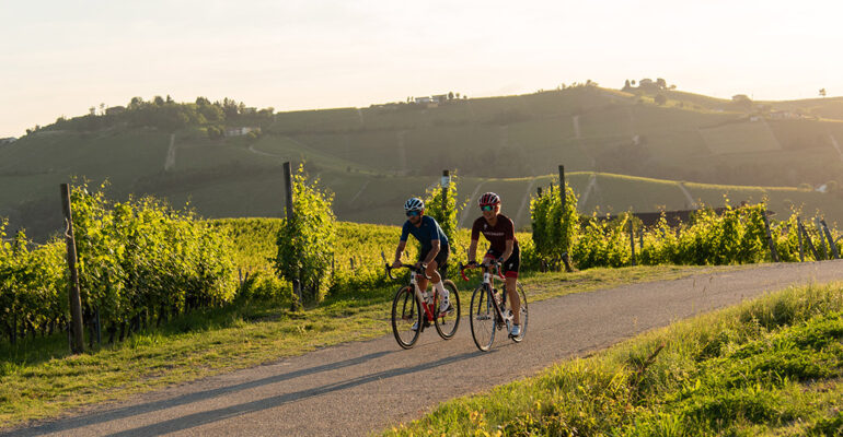 Deux cyclistes roulent au milieu des vignes du piemont