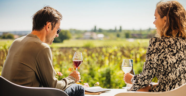 Un couple déguste du vin avec une vue sur les vignes