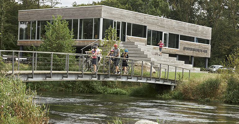 Une famille de cycliste traverse un pont en campagne