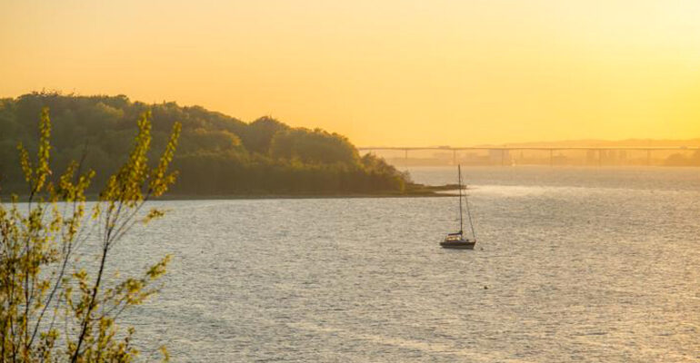 Un bateau vogue entre les fjords danois au coucher du soleil