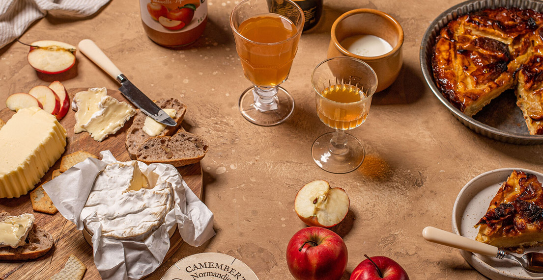 Table remplie de spécialités Normande camembert, tarte au pomme, cidre...