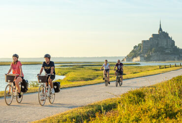 Un groupe de cycliste roule le long de la route menant au Mont Saint-Michel