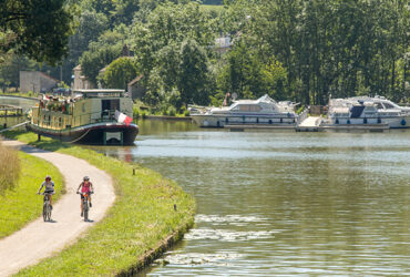 Un couple de cycliste roule sur la voie verte du Canal de Bourgogne et ses péniches