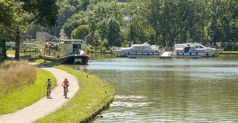 Un couple de cycliste roule sur la voie verte du Canal de Bourgogne et ses péniches