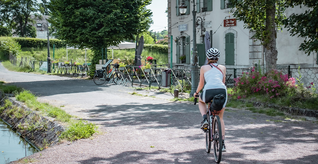 Une cycliste gravel roule le long des caneaux sur un chemin de halage