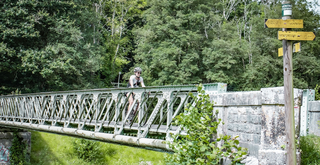 Une cycliste gravel traverse un pont en metal