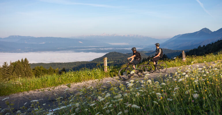 Deux cyclistes surplombent un lac et des montagnes