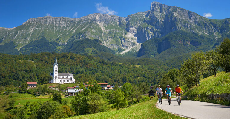 Un groupe de cycliste roule sur une route entourée de forêt et montagnes