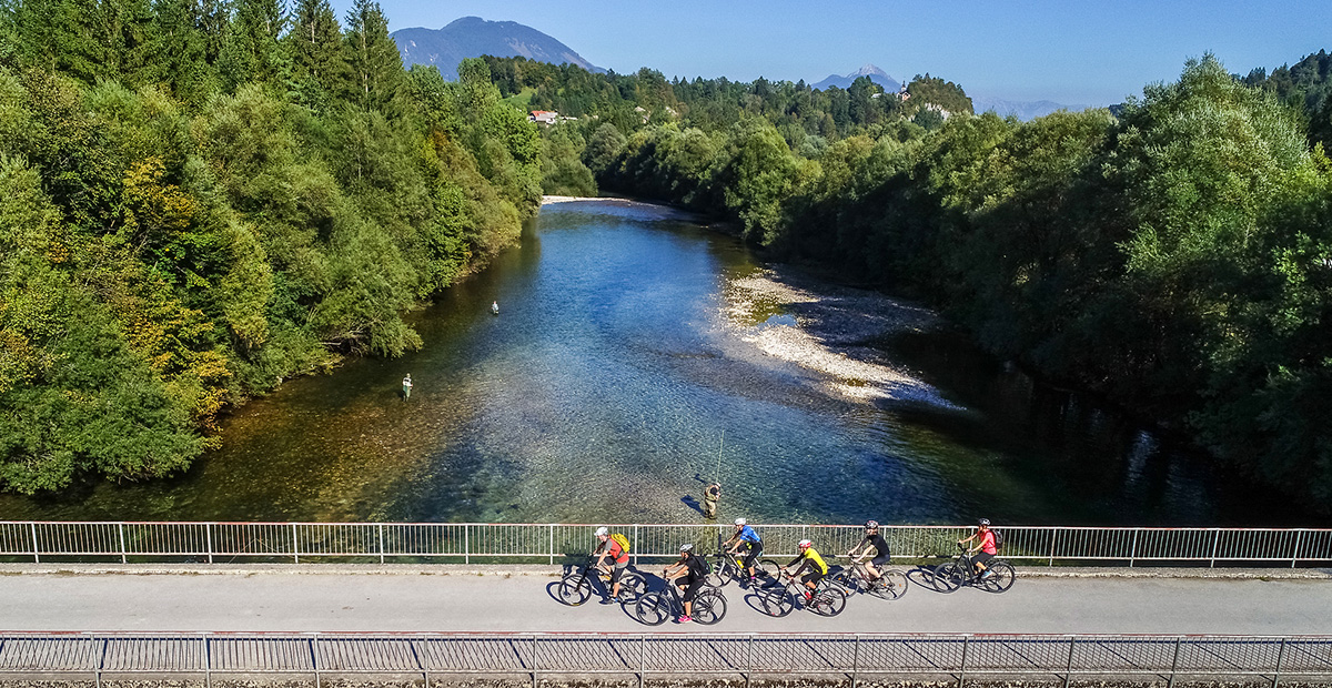 Un groupe de cyclistes traverse un pont au dessus d'une rivière