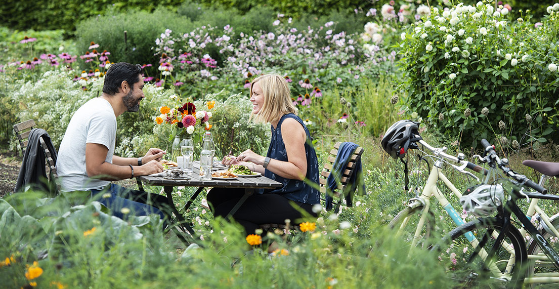 Un couple de cyclistes dejeunent a table avec leurs velos a cote