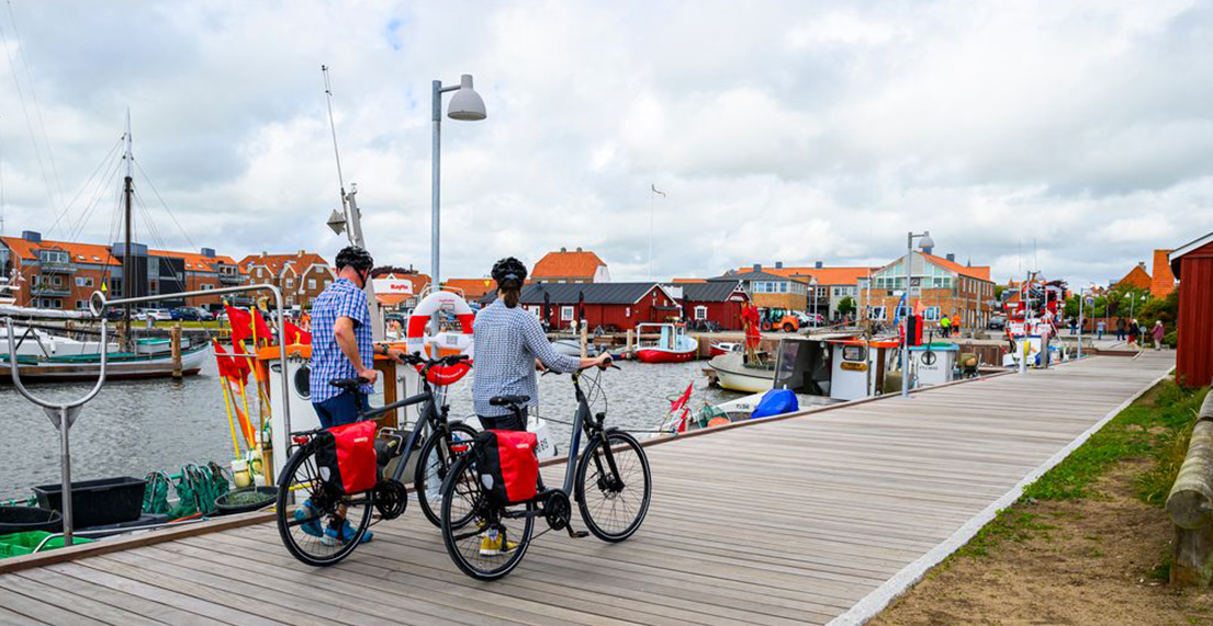 Un couple de cyclistes se promène dans un village de cabanes rouges