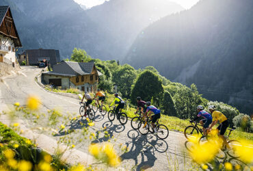 Un groupe de cycliste monte un col en traversant un petit village
