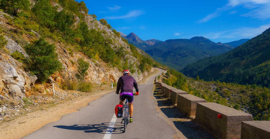 Un cycliste roule sur un route de montagne