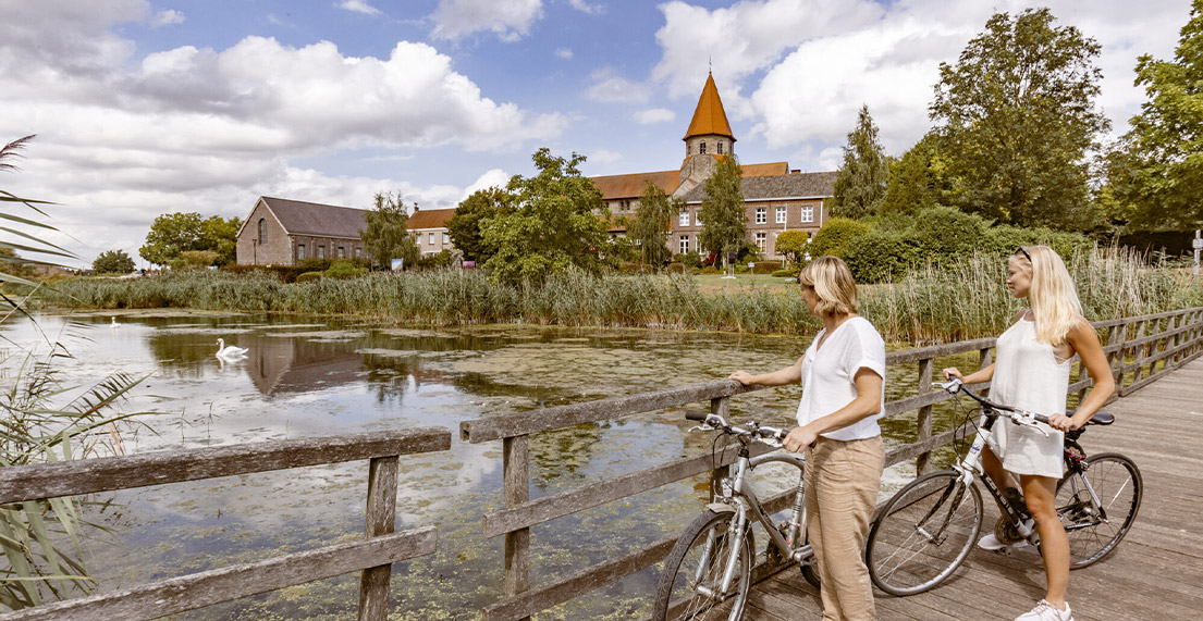 Deux femmes a velo admirent un petit village bucolique en campagne
