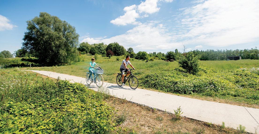 Un couple de cyclistes roule sur un chemin de halage en campagne