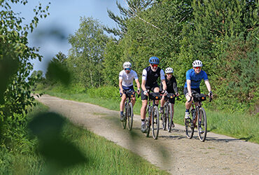 Un groupe de cyclistes roule ensemble sur un chemin entouré de forêt