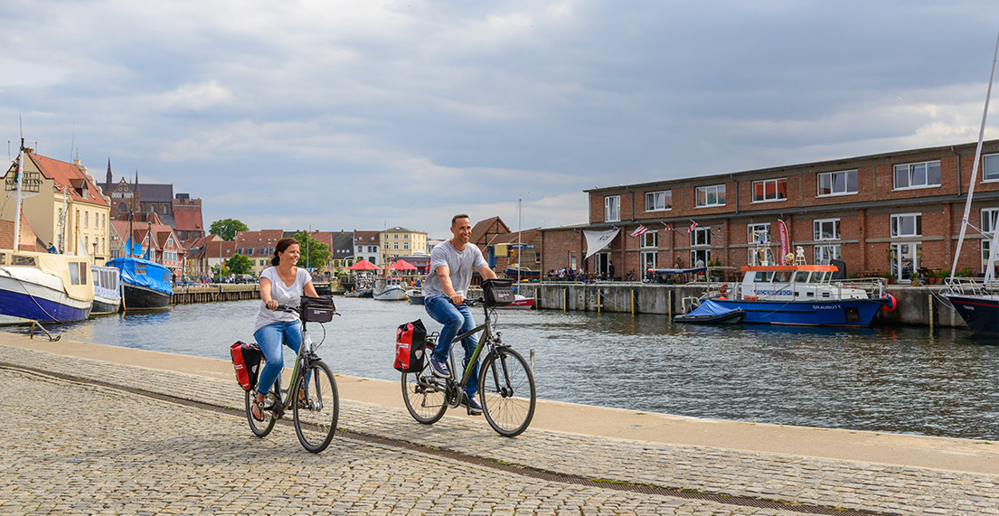 Un couple de cylistes roule le long d'un port