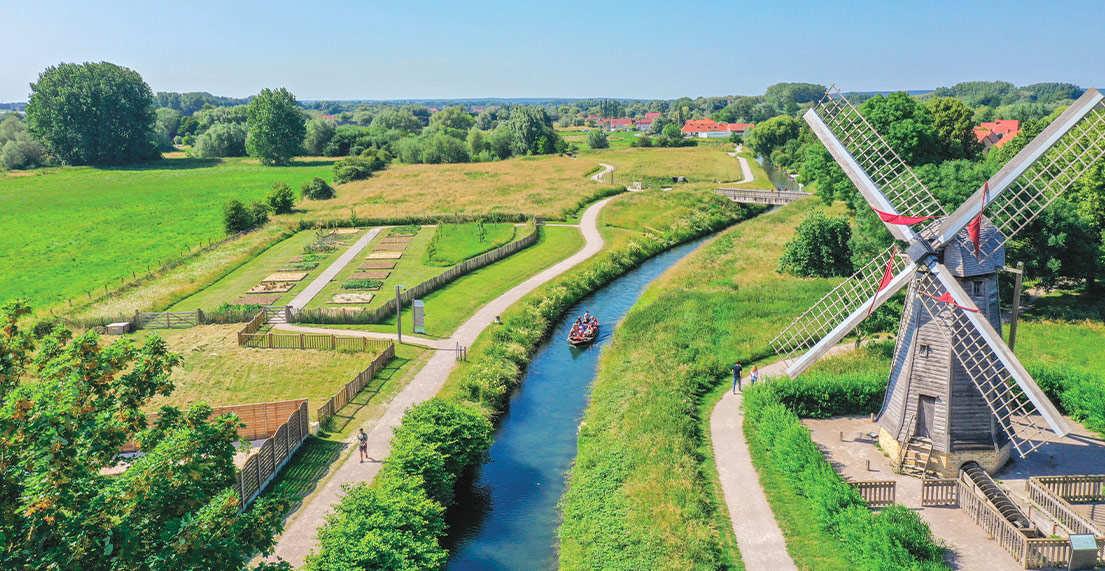Un paysage de campagne et son moulin à vent traversé par une rivière